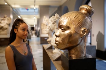 a young person looking at a statue head in the V&A