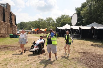 Four people at Glastonbury on a field, including a wheelchair user 