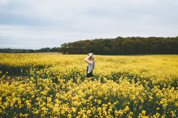 a model in the middle of a field, surrounded by yellow flowers